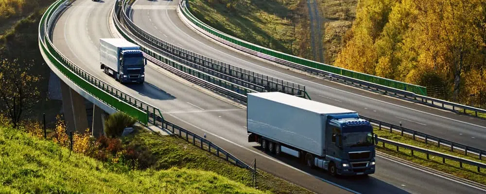 two long haul trucks driving on highway