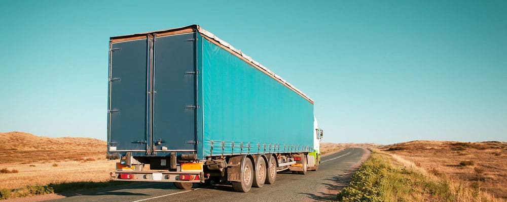 blue freight truck on desert highway