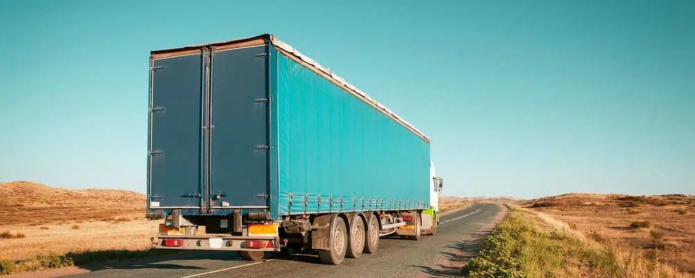 blue freight truck on desert highway