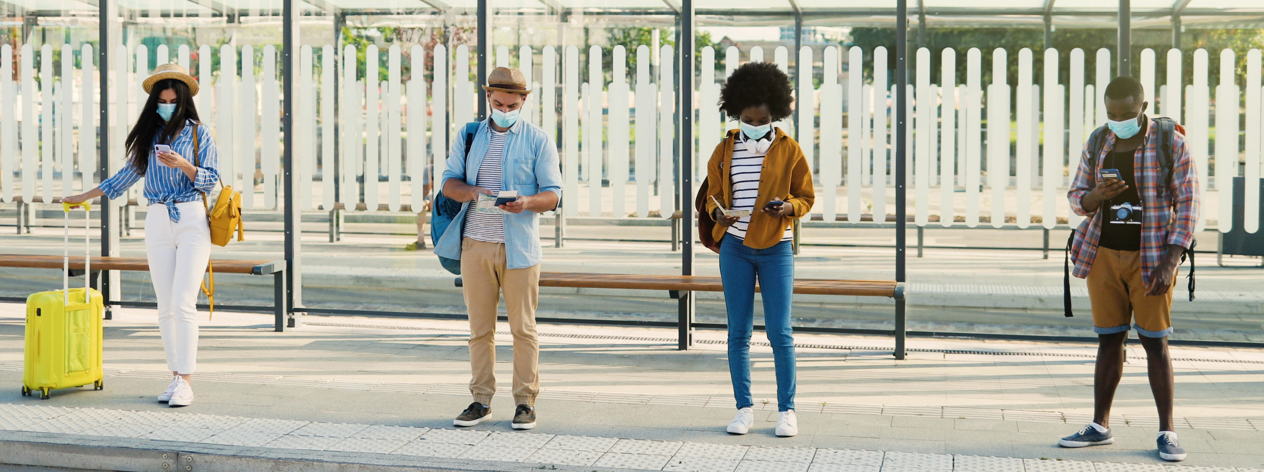 riders with masks wait at bus stop